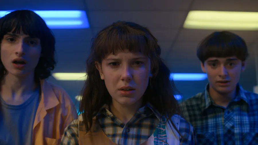 Finn Wolfhard como Mike Wheeler, Millie Bobby Brown como Eleven y Noah Schnapp como Will Byers en Stranger Things.