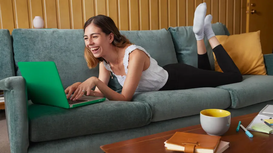 chica sonriendo en sillón con computadora
