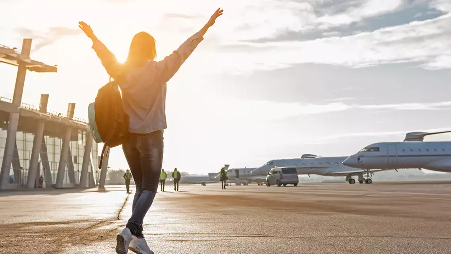 imagen de joven levantando los brazos para celebrar que está por abordar el avión que la lleva a sus próximas vacaciones de verano.