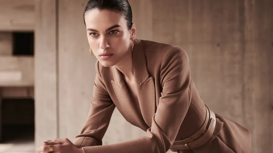 Una mujer, modelo, con un abrigo color café de la marca de El Palacio de Hierro, DHierro.