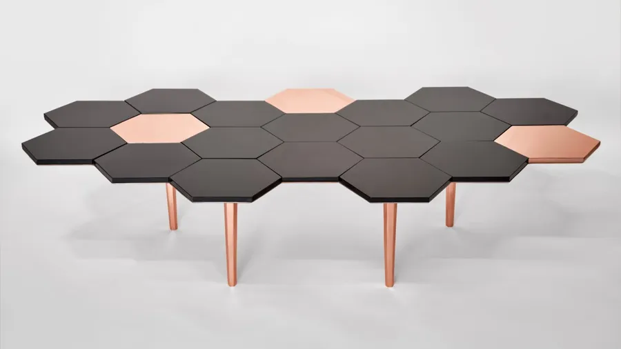 Se aprecia la mesa Honeycomb, creación de Sten Studio, misma que tiene una forma de panal de abeja en colores negro y dorado.