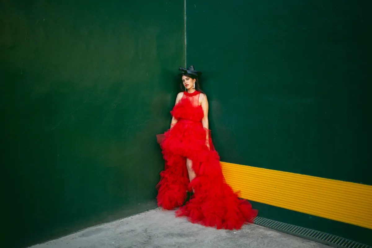 En un vestido rojo, asimétrico con corte halter y mucho volumen.