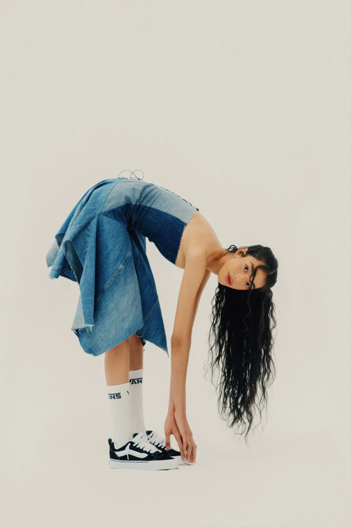Una mujer viste con los Vans Knu Skool y un vestido azul de mezclilla