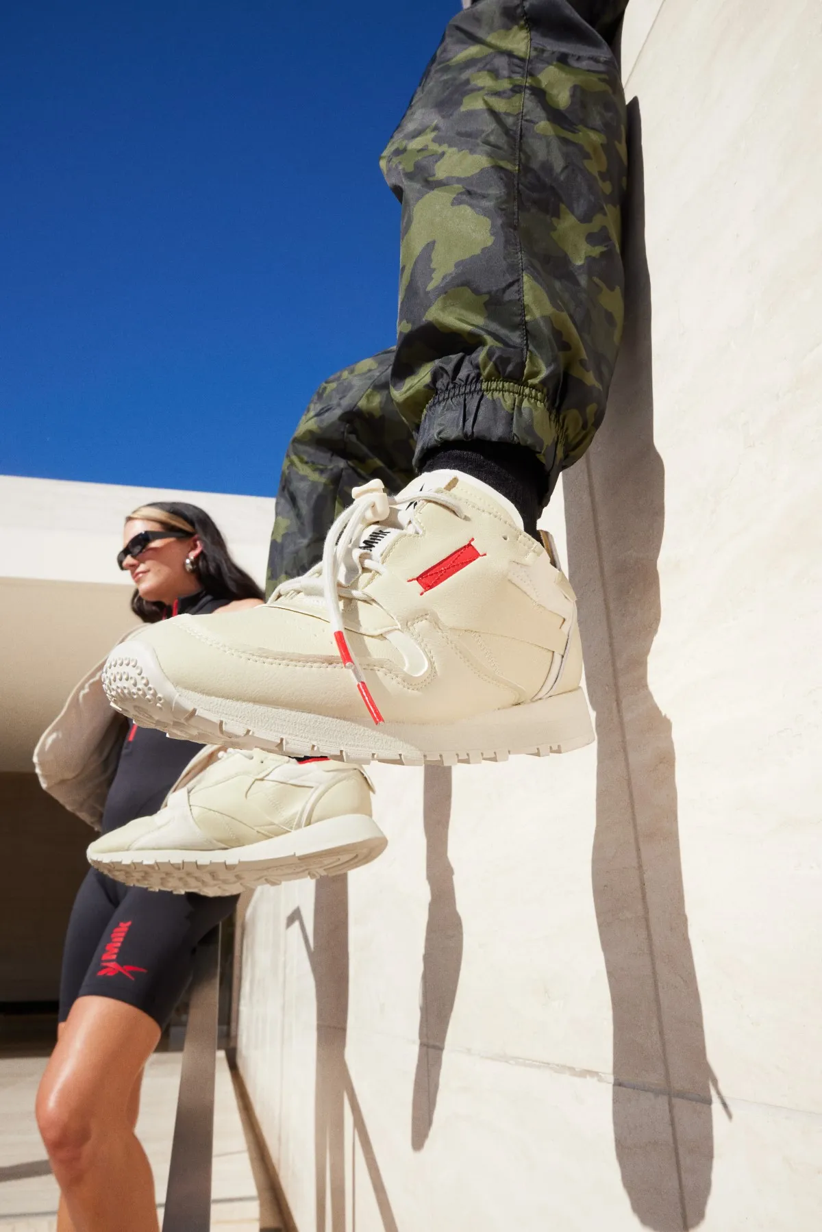 Dos modelos, hombre y mujer, posan sobre una barda con los Reebok Milk, tenis 100 % veganos