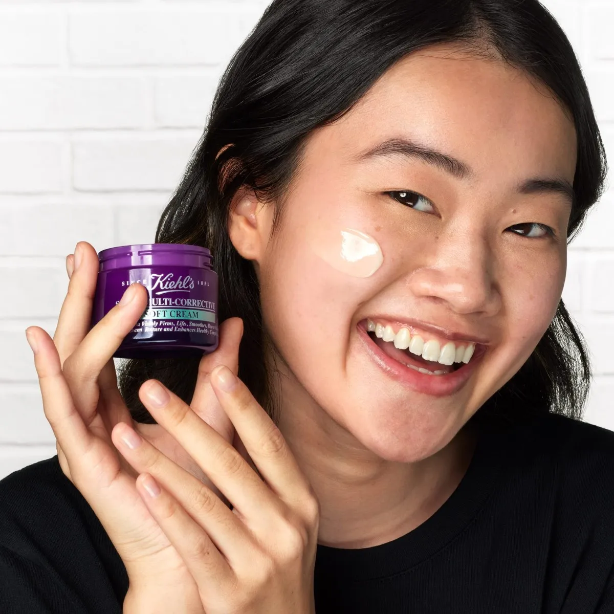 Mujer con la nueva Kiehl's Super Multi Corrective Soft Cream, aplicada en su rostro.