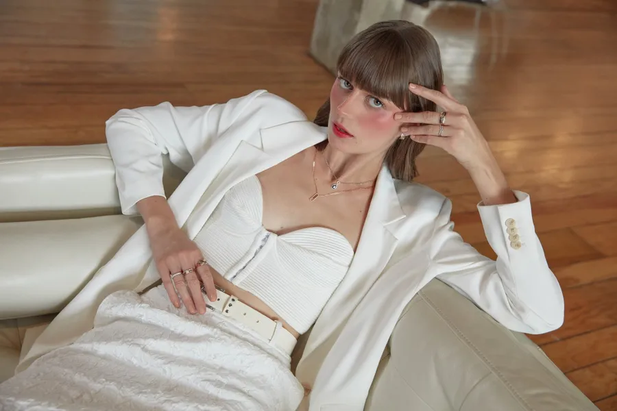 Una modelo vestida con pantalón, top y saco en color blanco; luce los diamantes cafés de Joyerías BIZZARRO.