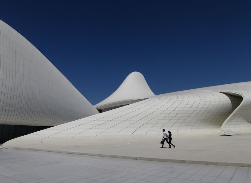 Two people walk across the plaza at the Zaha Hadid designed Heydar Aliyev Center in Baku, Azerbaijan