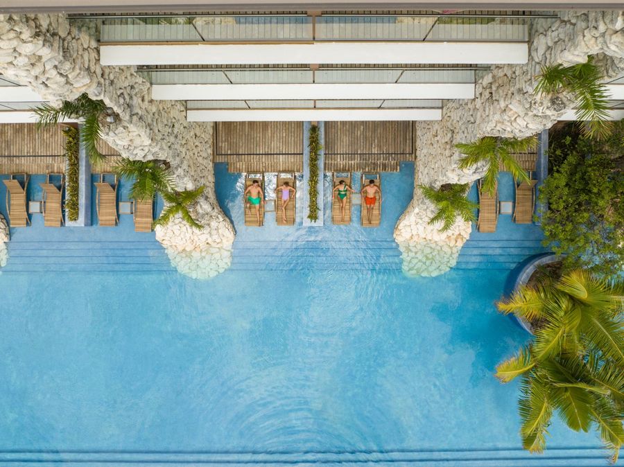 Dos parejas están disfrutando frente a una piscina, en las instalaciones y con el servicio de Hotel Xcaret México.